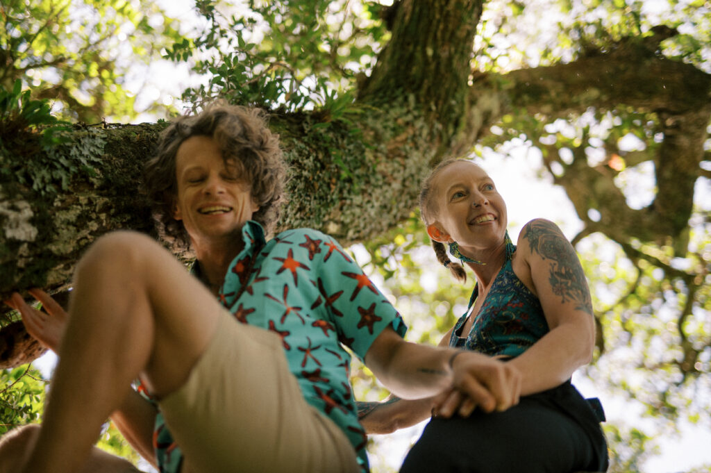 zach and carrie of bigger life adventures share a laugh in a tree on mindfulness retreat