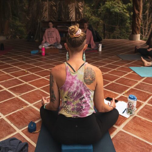 Yoga teacher sitting in a cross-legged seat on yoga deck in Mexico.