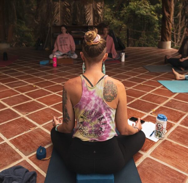 Yoga teacher sitting in a cross-legged seat on yoga deck in Mexico.